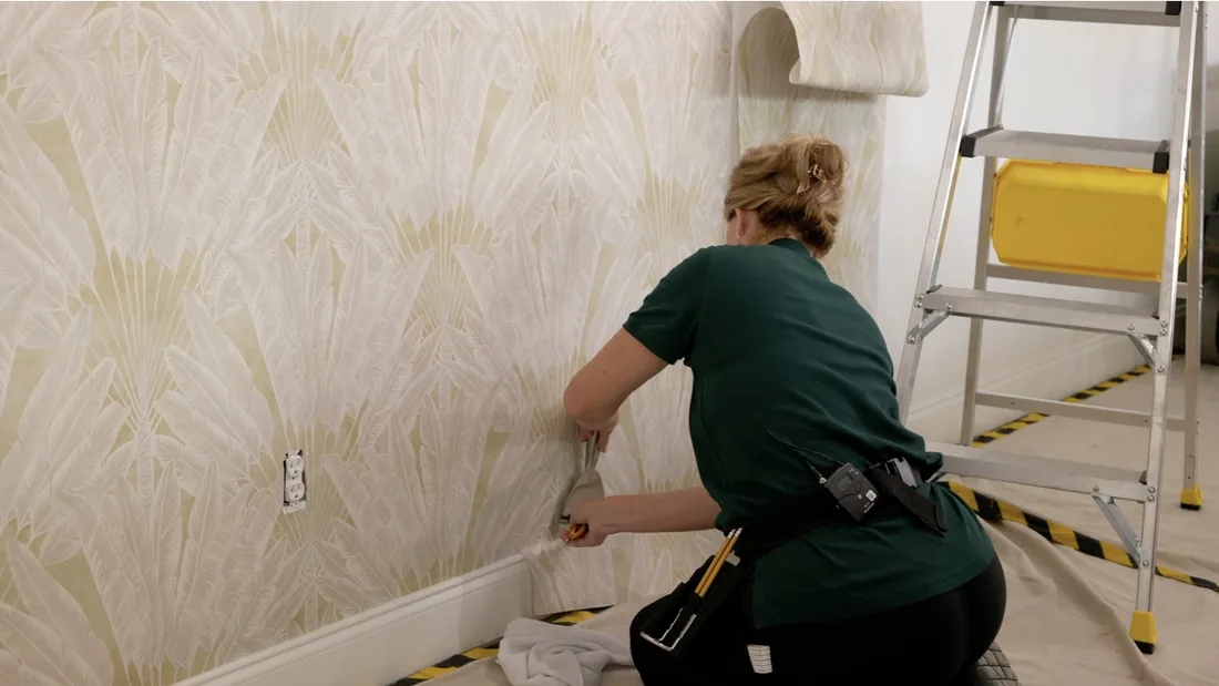 Wallpaper installer smoothing a patterned wallcovering with care
